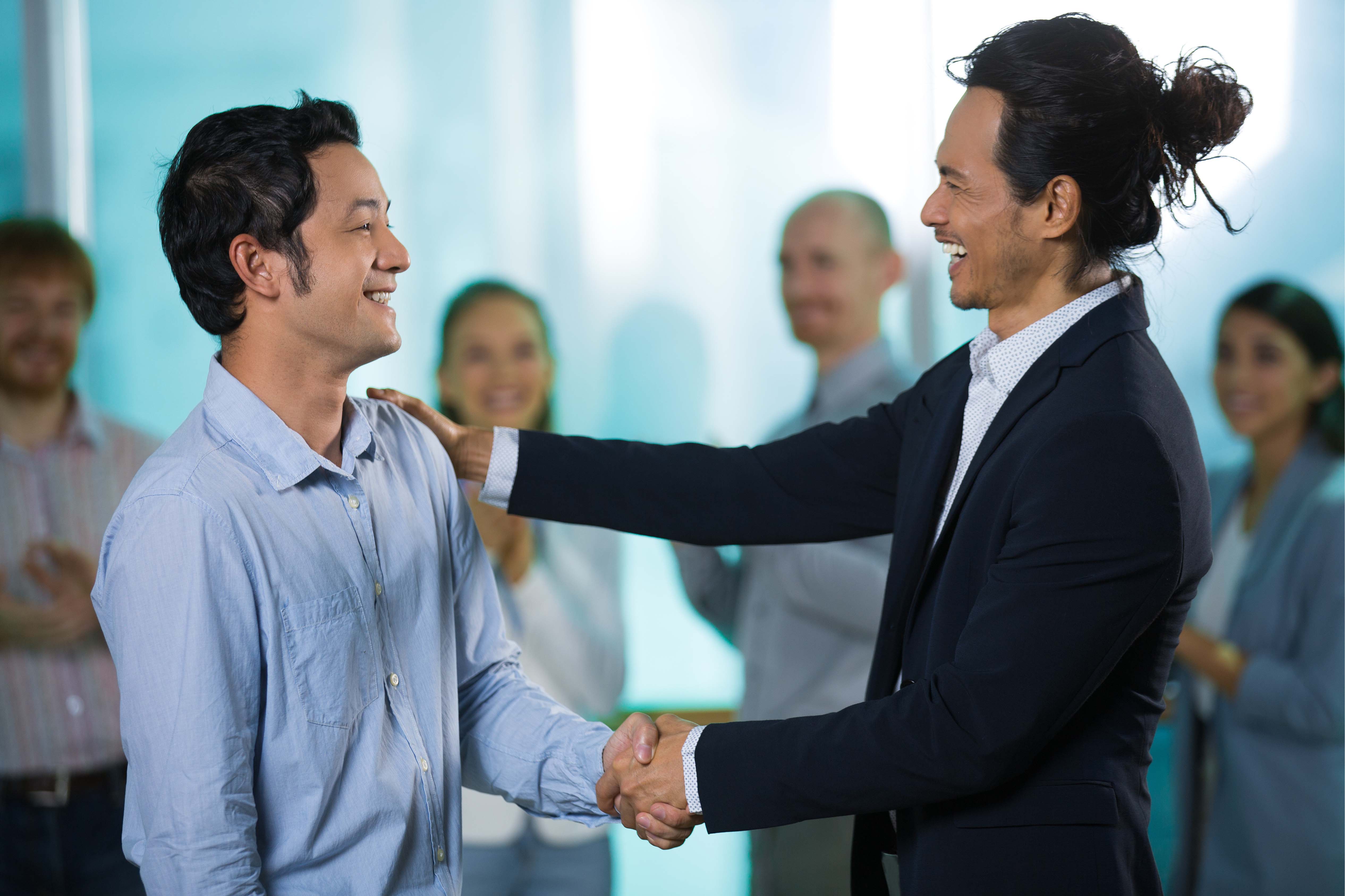 Celebratory handshake between colleagues in a diverse modern office setting