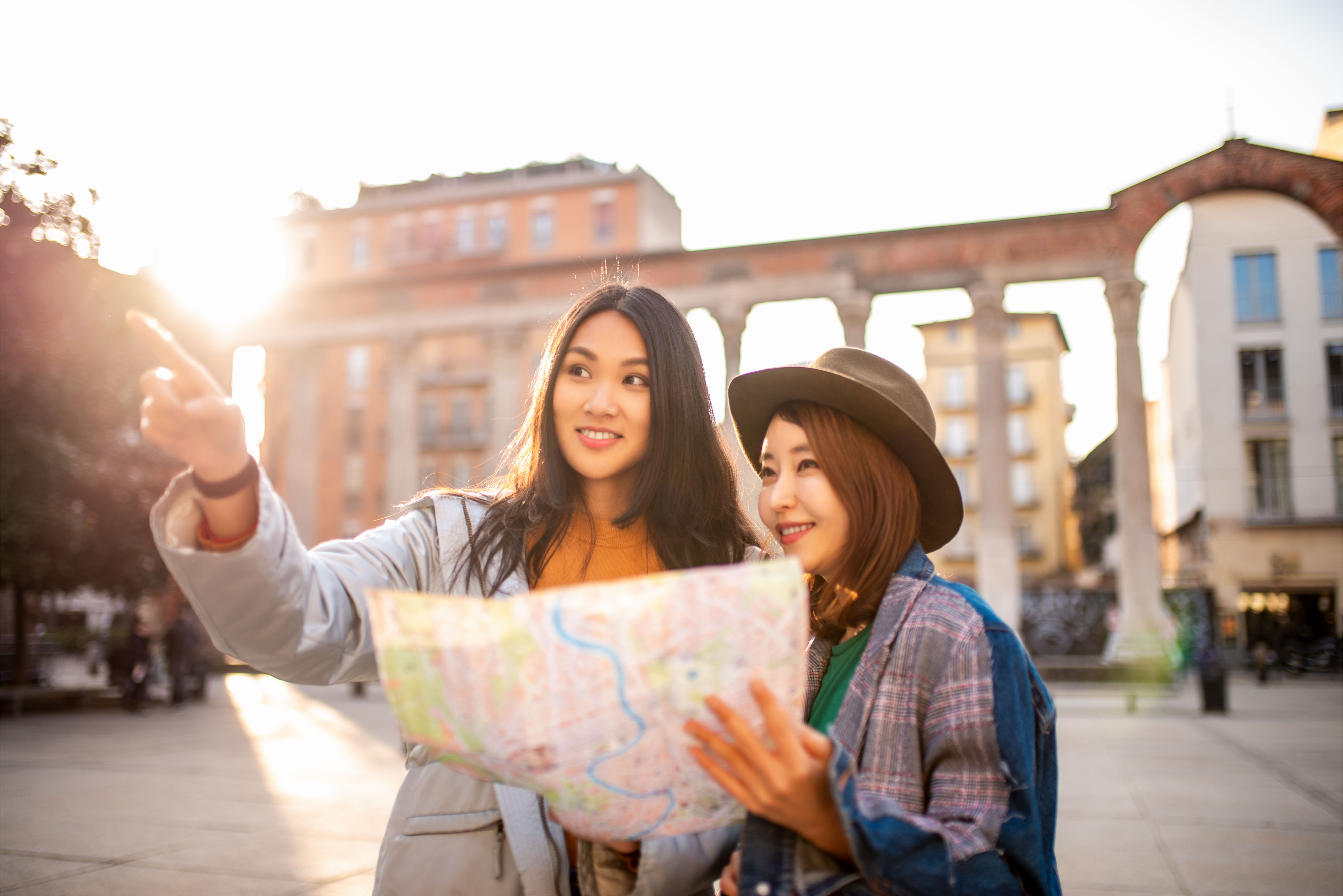 Two young travellers exploring a historic city with a map at sunset