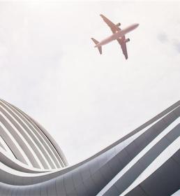 plane flying near modern building