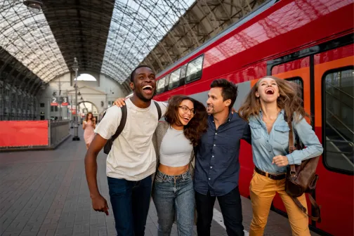 Diverse group of friends arriving at a train station, smiling and enjoying their journey together