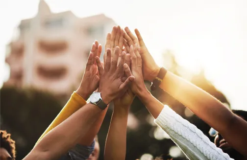 Team unity and celebration with a group high five in sunlight