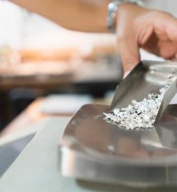 A jeweller pours particles of silver onto a scale