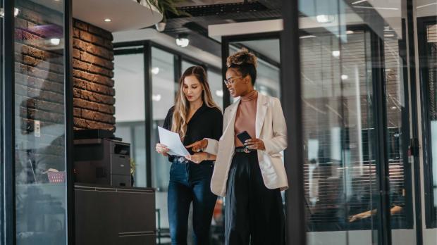 Young female employees walking down the company corridor Young female employees walking down the company corridor