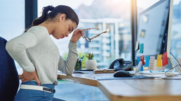 Les troubles musculosquelettiques impactent la performance des salariés Une jeune femme travaillant dans un bureau souffre de mal de dos