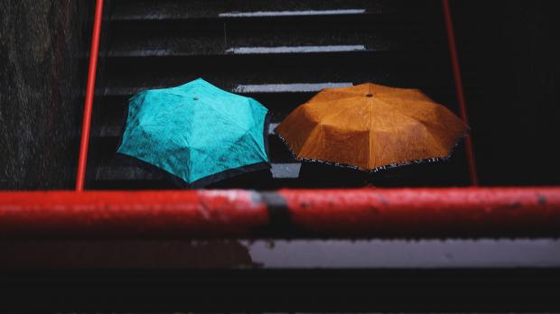 A blue and an orange umbrella in the rain