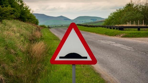 Bump in the road sign by road with background of hills