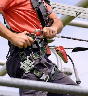 A construction worker ties a safety harness to climb an electricity pylon
