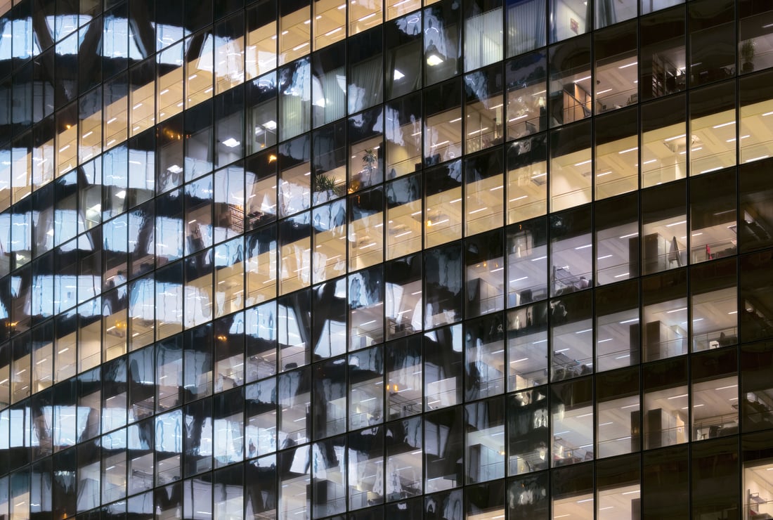 Reflection of Illuminated office building in glass office facade in Paris, France.