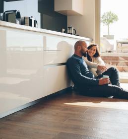 A couple sit on the floor of their luxury modern kitchen