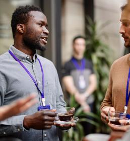 Employee drinking black coffee while standing with colleagues