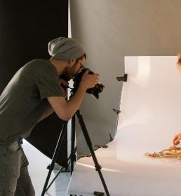 A person taking a photo of a woman in a studio