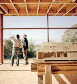 Two men discussing a house plan in daylight