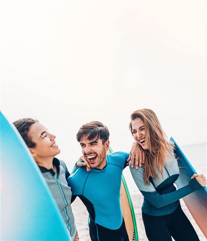 3 friends on beach with surfboards