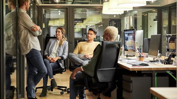 Team sitting and talking at their desks Team sitting and talking at their desks