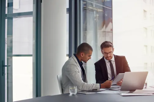 Two business men sitting as a desk looking at documents
