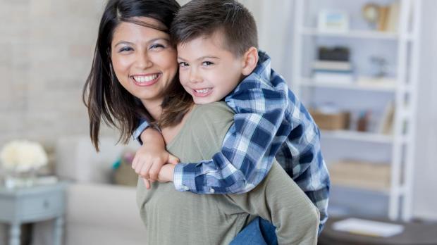 Smiling mother with her son on her back