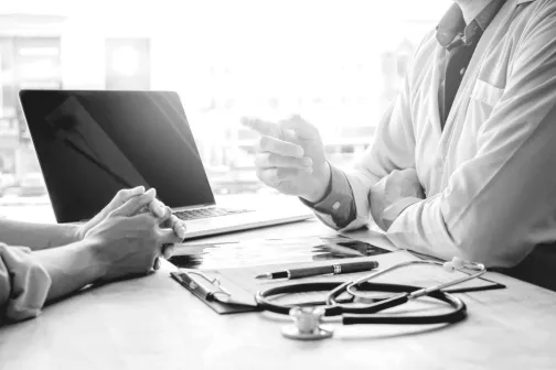 Doctor pointing at a patient over his desk
