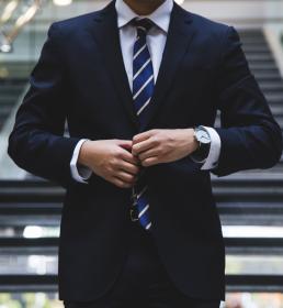 Corporate businessman in a suit and tie doing his button up