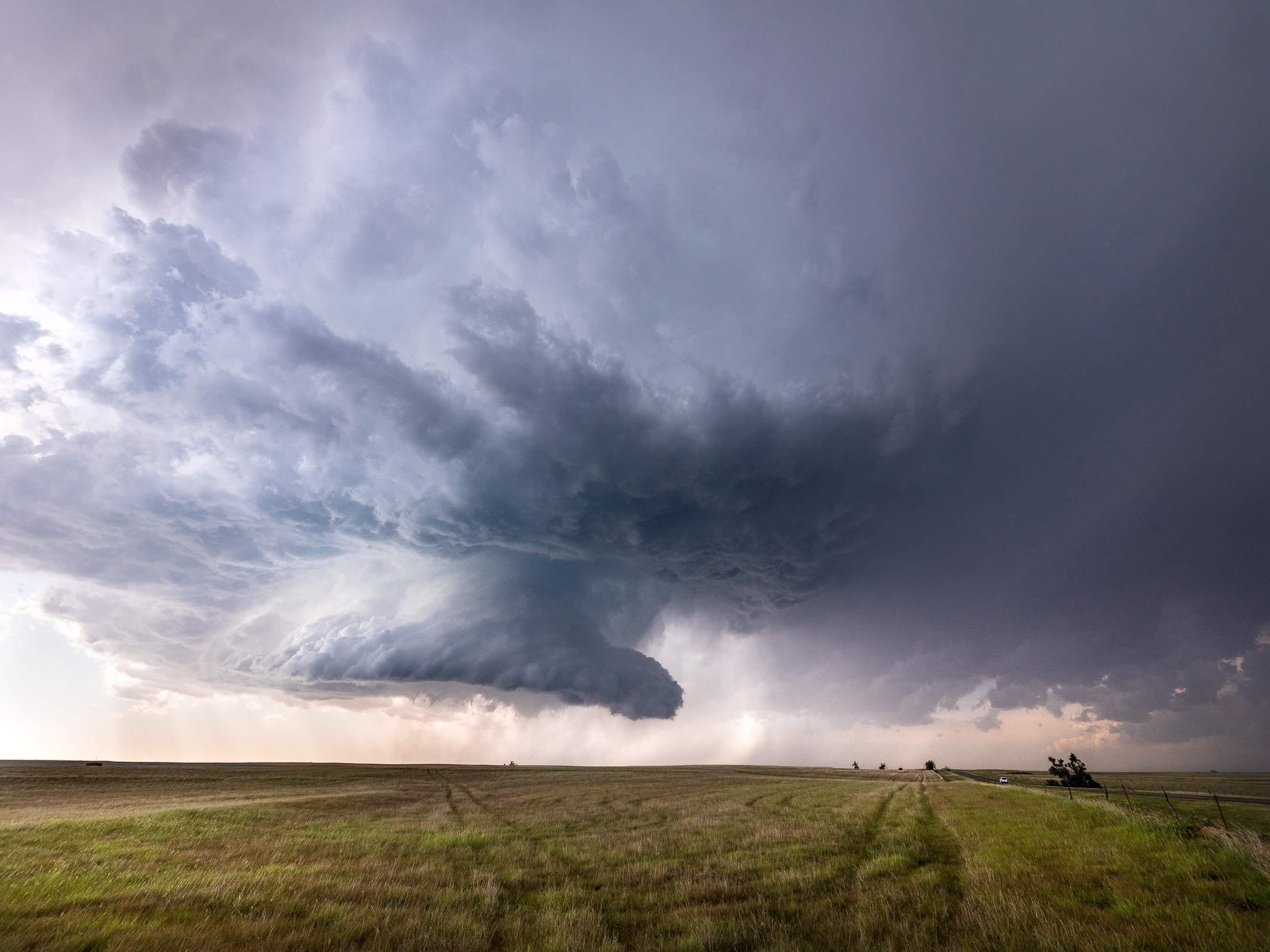 Massive supercell thunderstorm over open plains with dark storm clouds, severe weather system, tornado formation, and dramatic atmospheric conditions.